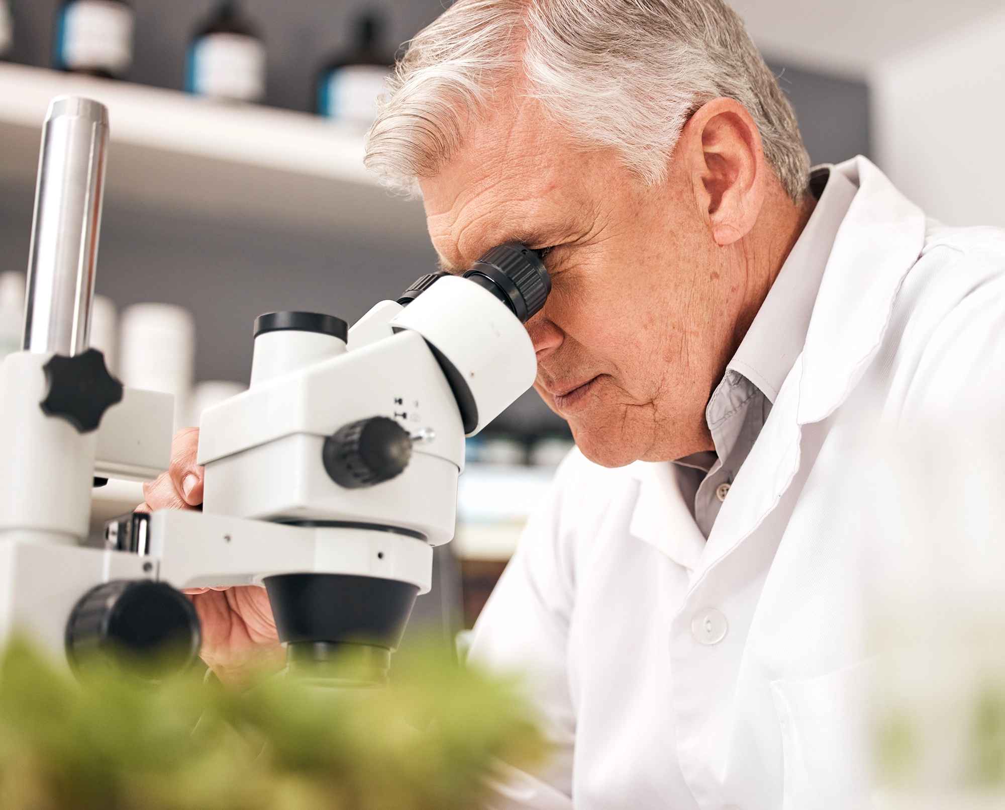 Man in white lab coat looking into microscope Man in white lab coat looking into microscope